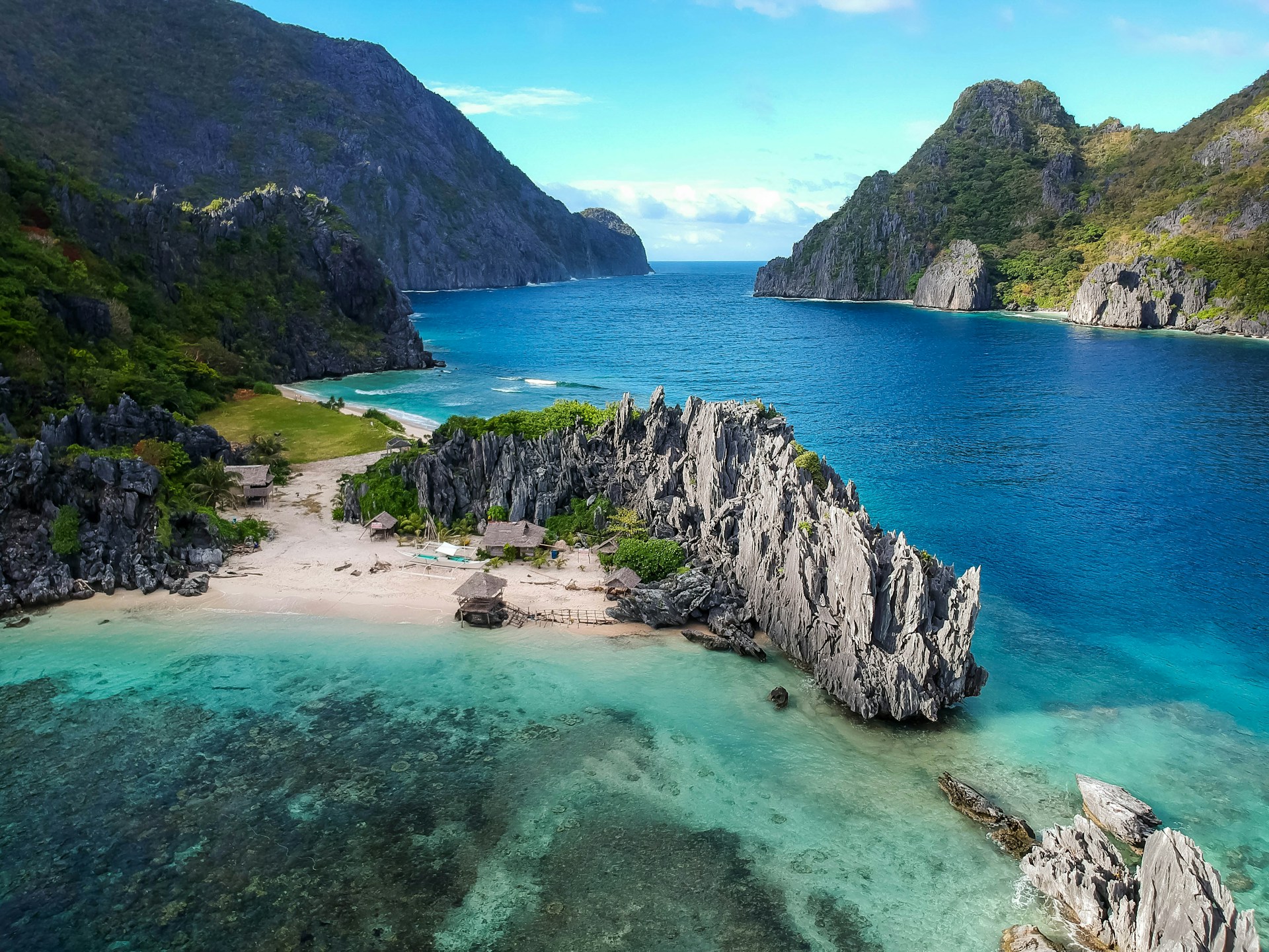 beach with sharp jagged rocks and clear blue water.